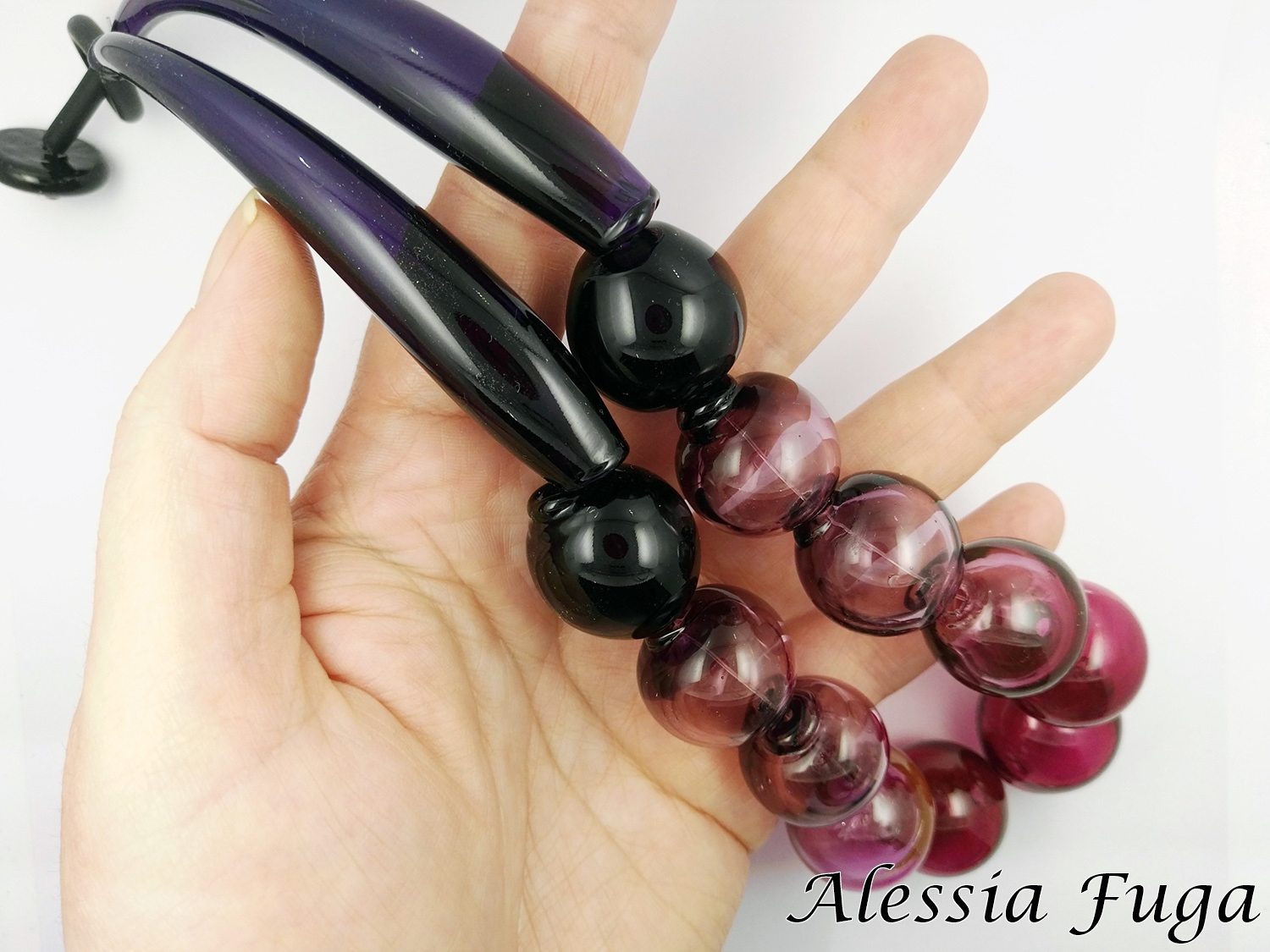Collana girocollo in vetro soffiato in rubino e glicine tenuta in mano