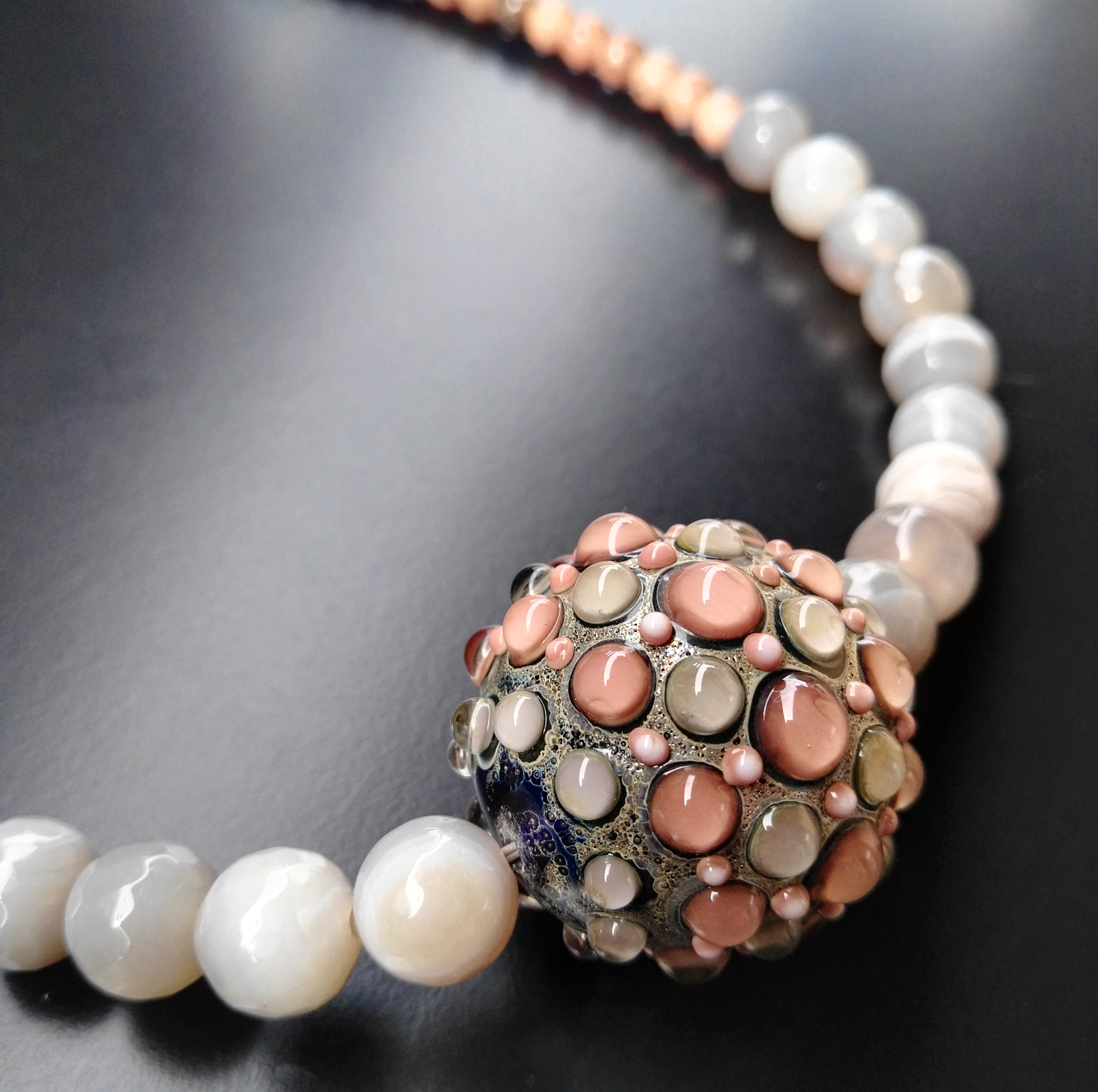 Particolare di collana fenice in rosa antico e grigio