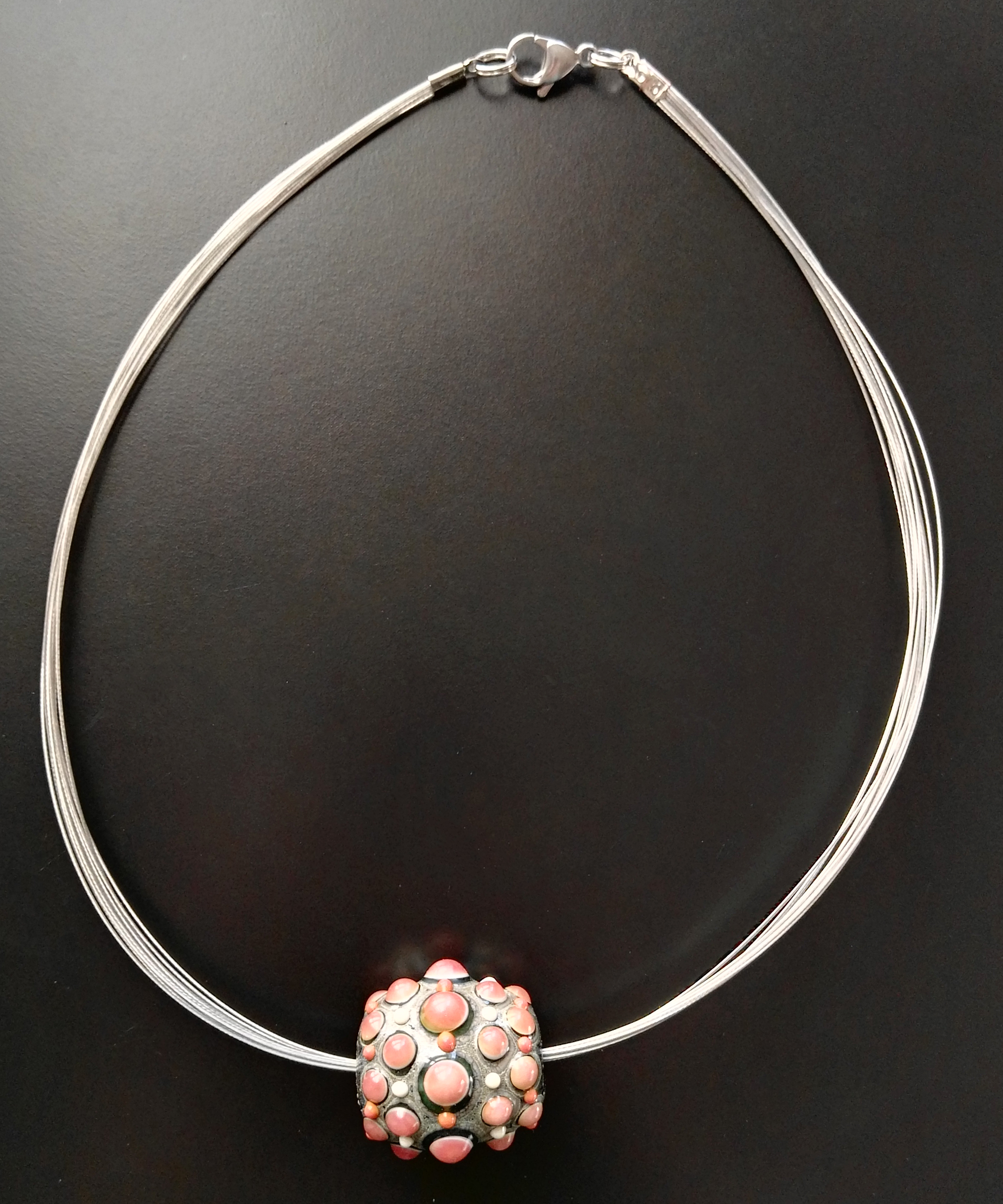Visione intera di collana con perla di vetro rosa e grigio su cavetto di acciaio