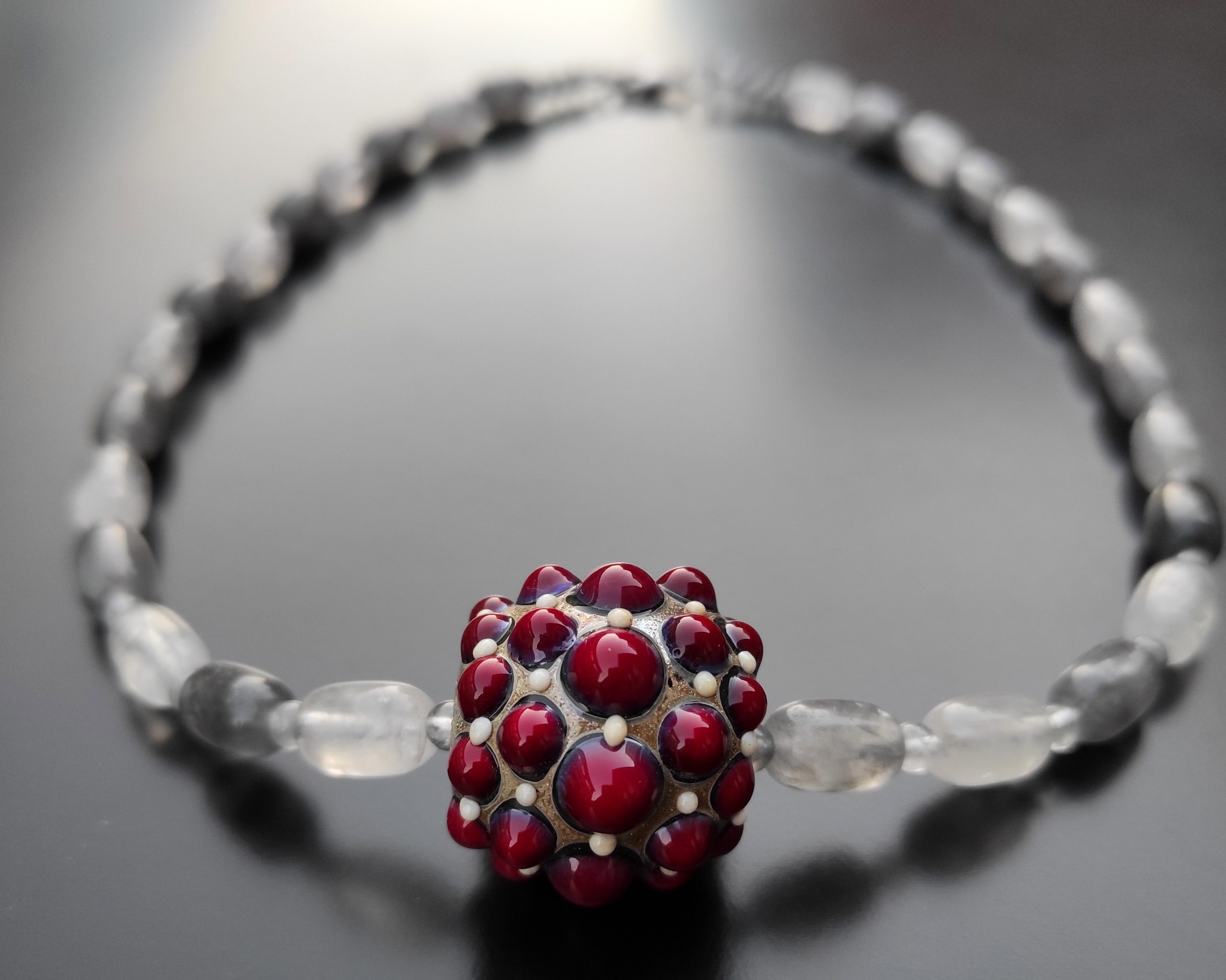 quarzo grigio e perla in vetro di Murano rosso2 Visione da vicino di perla fenice in rosso su collana con quarzo grigio